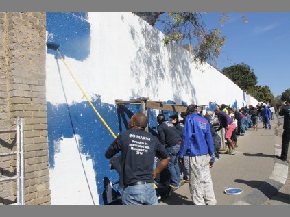 Marsh staff members, pupils, staff and school governing body members of Alex High busy at work painting the school wall on Mandela Day.