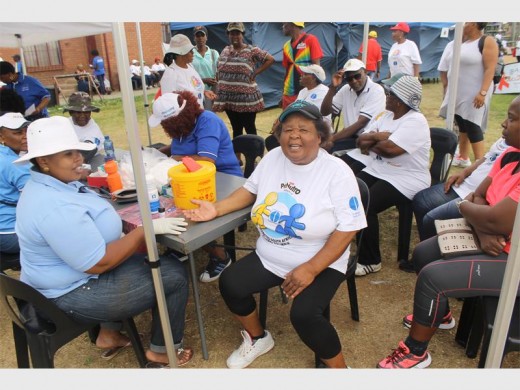 Tseki Dibate of the City's health department tests Annah Mphuthi for diabetes at a health-related event.