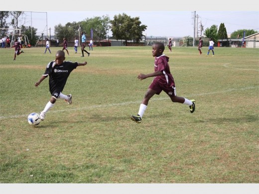 AN ITHUTE player (black) crosses the ball as his Iphutheng counterpart closes in to try and block it.